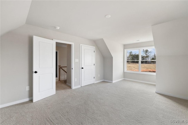 additional living space featuring light colored carpet and lofted ceiling