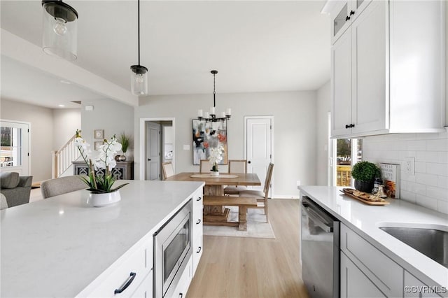 kitchen featuring pendant lighting, stainless steel appliances, decorative backsplash, and white cabinets