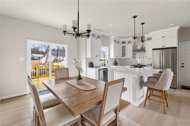 dining room with sink, an inviting chandelier, and light wood-type flooring