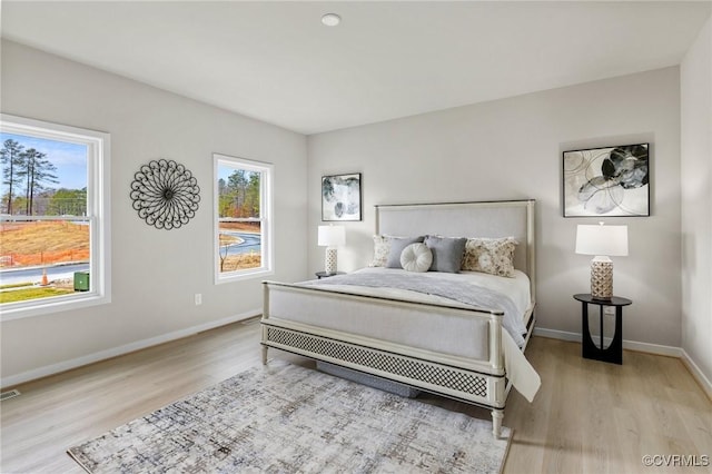 bedroom with light hardwood / wood-style floors and multiple windows