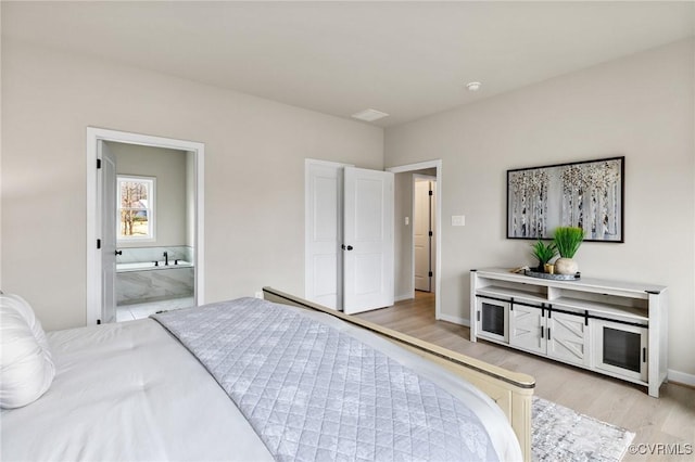 bedroom with ensuite bathroom and light wood-type flooring