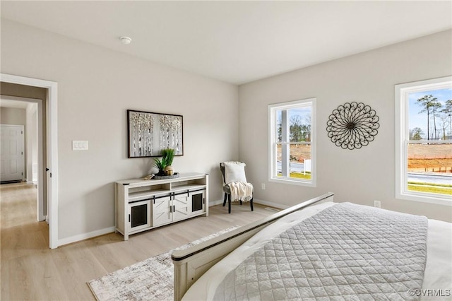 bedroom with multiple windows and light hardwood / wood-style flooring