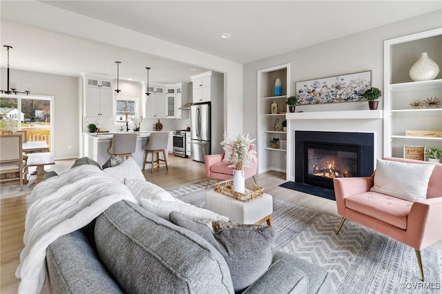 living room with built in features and light hardwood / wood-style flooring