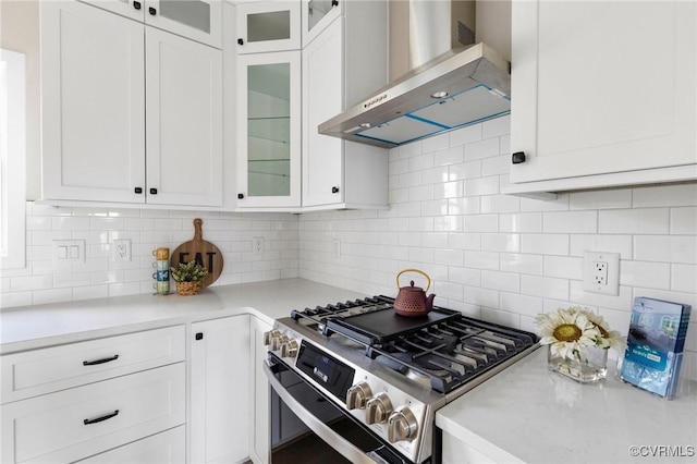 kitchen featuring white cabinetry, tasteful backsplash, gas stove, and wall chimney exhaust hood