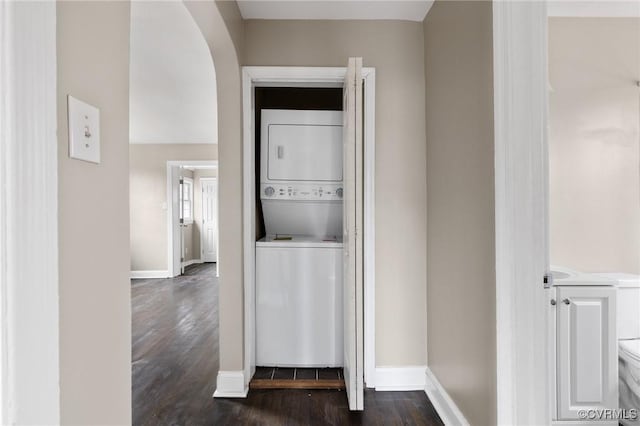 corridor with dark hardwood / wood-style flooring and stacked washer / drying machine