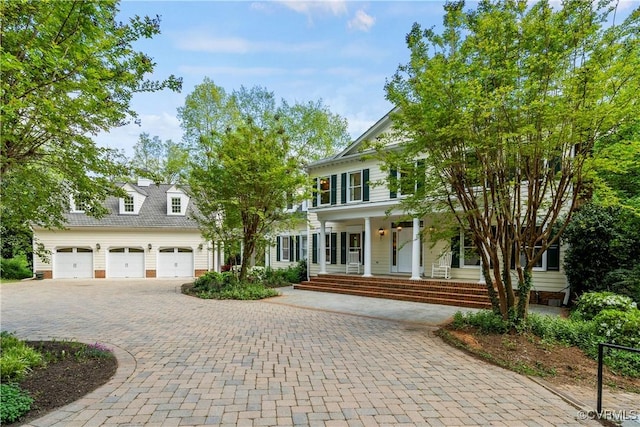 view of front of house with a porch, decorative driveway, and a garage