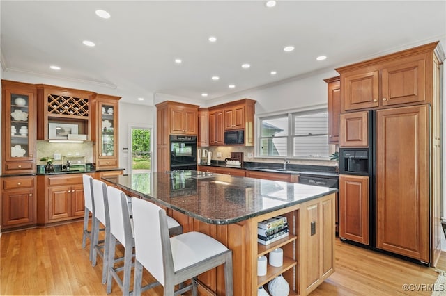 kitchen featuring black appliances, a kitchen island, glass insert cabinets, and dark stone countertops