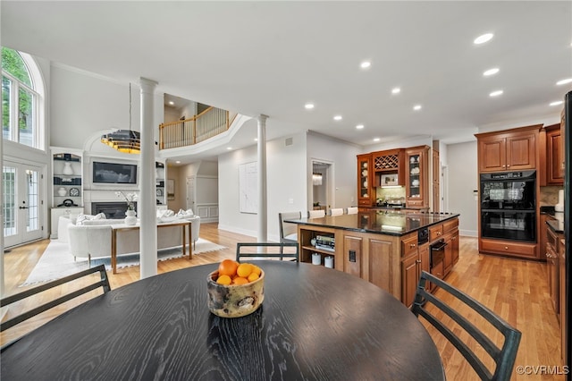 kitchen featuring dobule oven black, decorative columns, dark countertops, open floor plan, and a fireplace