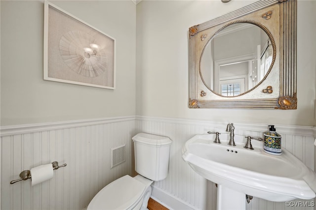 bathroom with a wainscoted wall, a sink, and visible vents