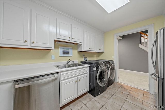 laundry area with laundry area, light tile patterned floors, baseboards, separate washer and dryer, and a sink