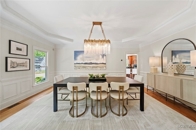 dining area featuring ornamental molding, visible vents, light wood-style flooring, and an inviting chandelier