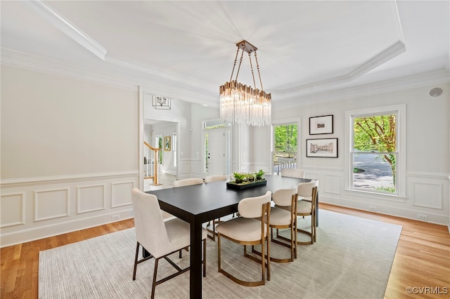 dining area with light wood-type flooring, crown molding, and stairway