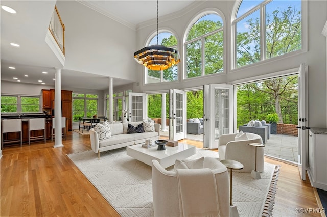 sunroom / solarium featuring a chandelier, french doors, and decorative columns