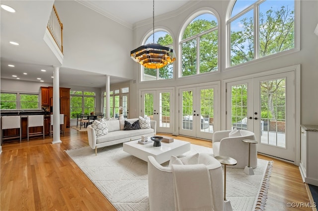 sunroom featuring ornate columns, an inviting chandelier, and french doors