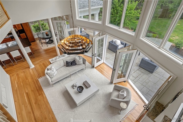 living room featuring a towering ceiling, wood finished floors, and french doors