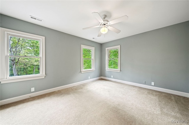 carpeted spare room featuring a ceiling fan, visible vents, and baseboards