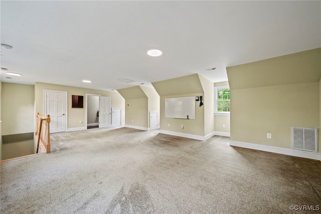 interior space with baseboards, visible vents, vaulted ceiling, and carpet flooring