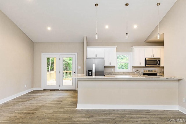 kitchen featuring wood-type flooring, pendant lighting, stainless steel appliances, light stone countertops, and white cabinets