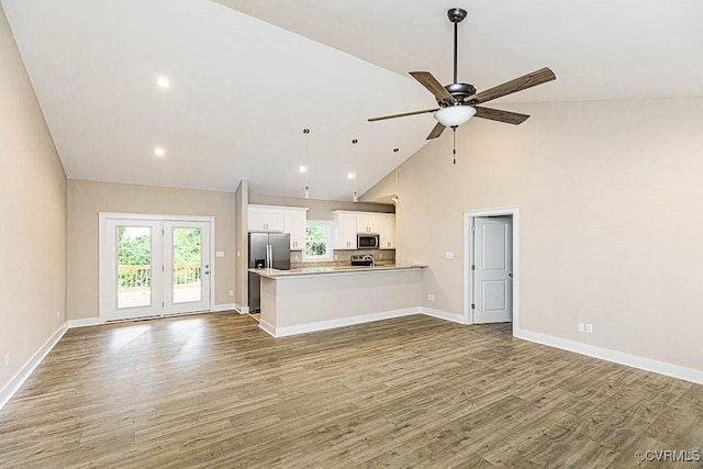 unfurnished living room with ceiling fan, wood-type flooring, and high vaulted ceiling