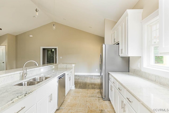 kitchen with sink, vaulted ceiling, appliances with stainless steel finishes, light stone countertops, and white cabinets