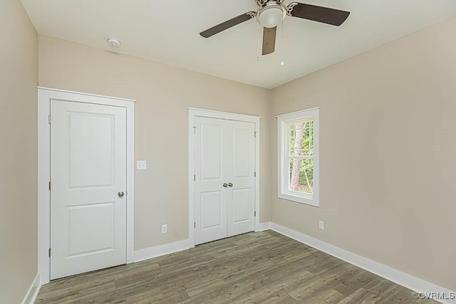 unfurnished bedroom with dark wood-type flooring, a closet, and ceiling fan