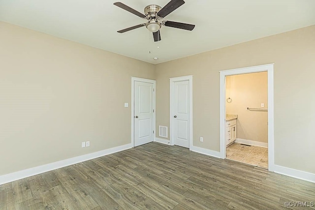 unfurnished bedroom featuring ensuite bathroom, ceiling fan, and light wood-type flooring