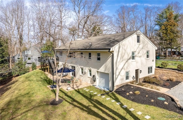 rear view of property featuring a patio area, a garage, a wooden deck, and a yard