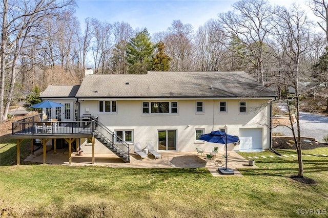 back of property with a garage, a lawn, and a wooden deck