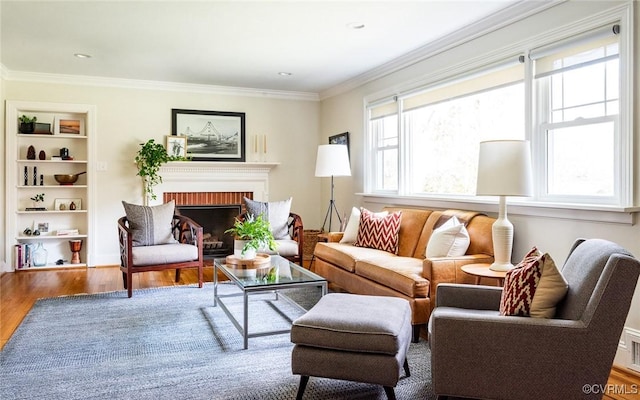 living room featuring a fireplace, ornamental molding, hardwood / wood-style floors, and built in features