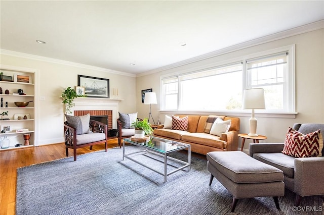 living room with a fireplace, hardwood / wood-style flooring, crown molding, and built in features