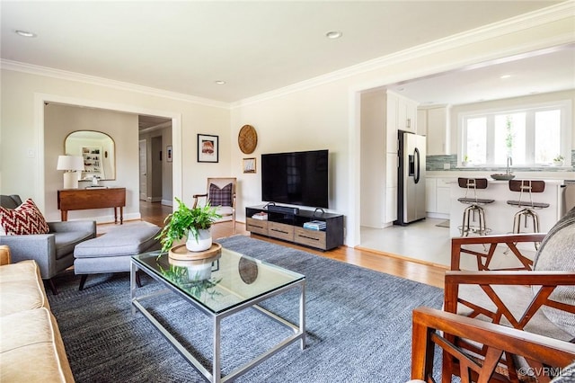 living room with sink, ornamental molding, and light wood-type flooring