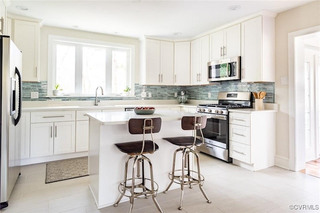 kitchen featuring white cabinets, a kitchen island, a breakfast bar area, and stainless steel appliances