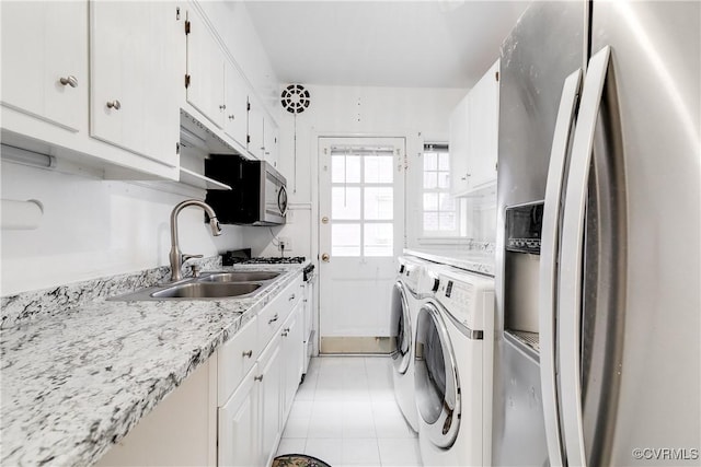 clothes washing area featuring sink, light tile patterned floors, cabinets, and washer and dryer