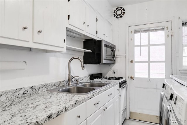 kitchen featuring white cabinets, plenty of natural light, gas range gas stove, and washing machine and clothes dryer