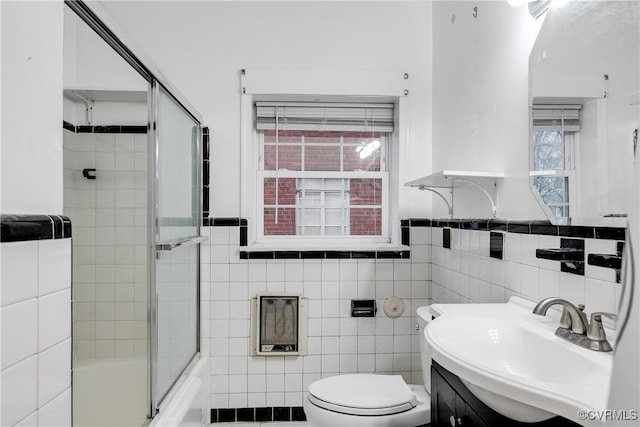 full bathroom featuring enclosed tub / shower combo, vanity, toilet, and tile walls