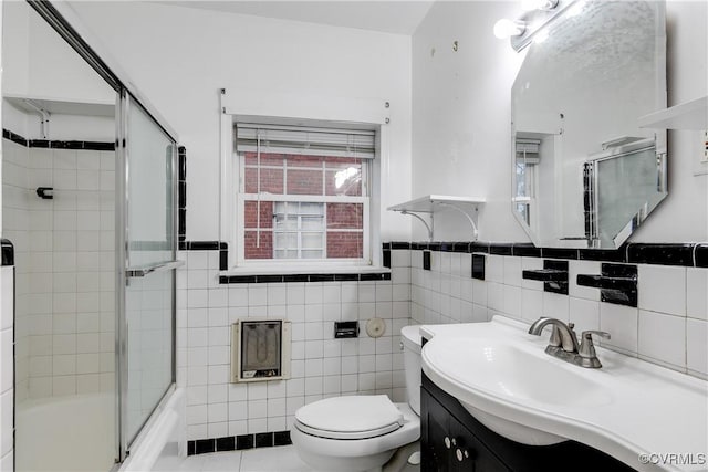 full bathroom with vanity, bath / shower combo with glass door, tile walls, and toilet