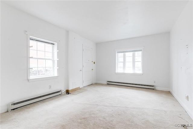 carpeted spare room with a wealth of natural light and baseboard heating