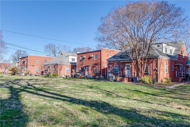 back of property with a yard and central AC