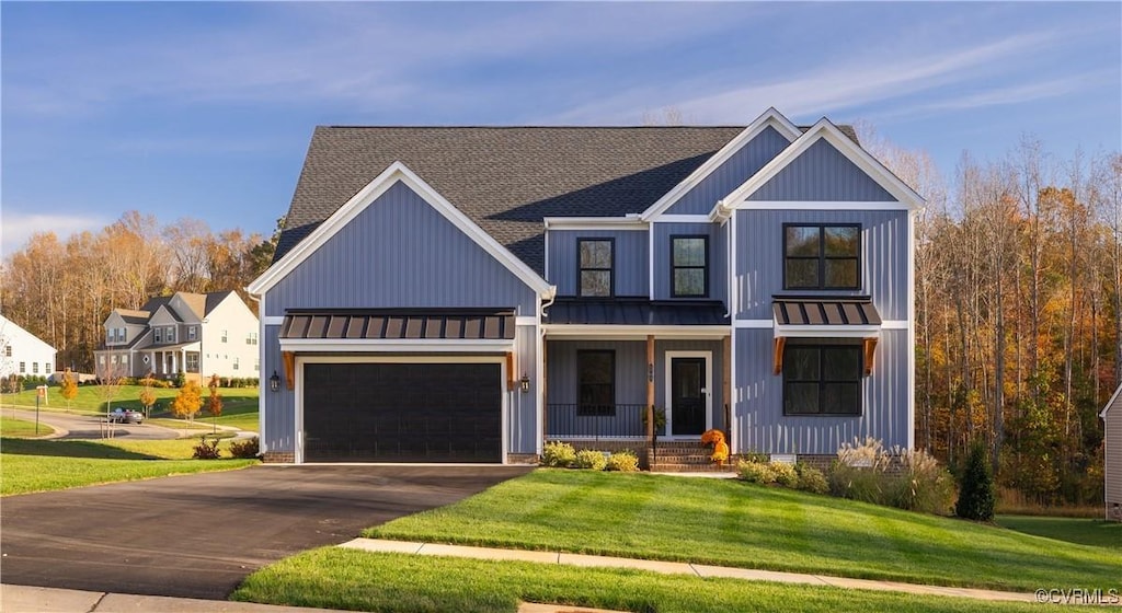 modern inspired farmhouse with a garage, a front lawn, and covered porch