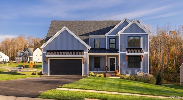 modern inspired farmhouse with a garage, a front lawn, and covered porch