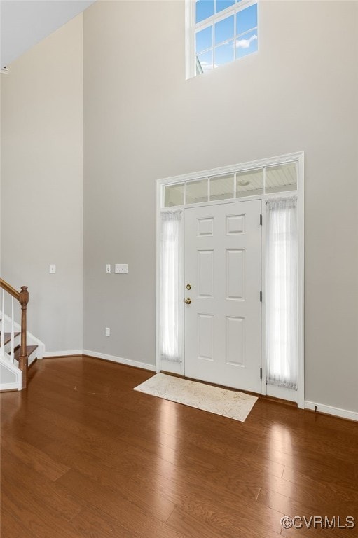 foyer with a towering ceiling and dark hardwood / wood-style floors