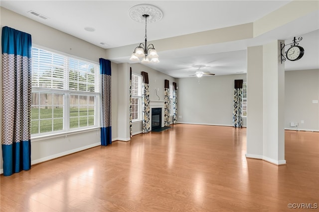 unfurnished living room featuring ceiling fan with notable chandelier and light wood-type flooring