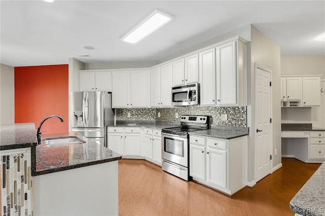 kitchen with appliances with stainless steel finishes, sink, white cabinets, and light hardwood / wood-style floors