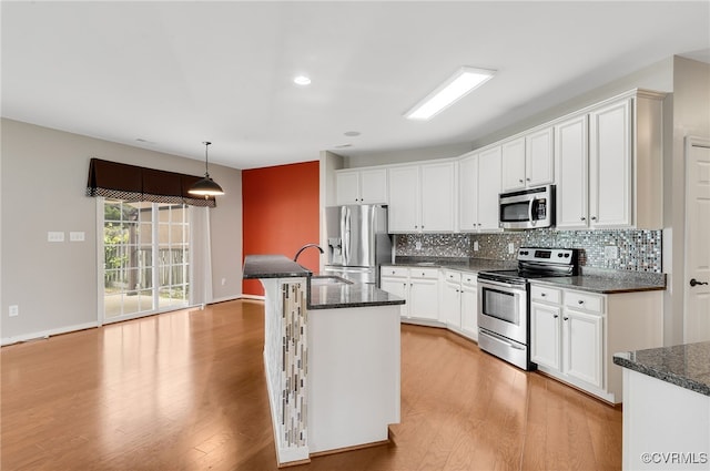 kitchen featuring decorative backsplash, stainless steel appliances, hanging light fixtures, and white cabinets