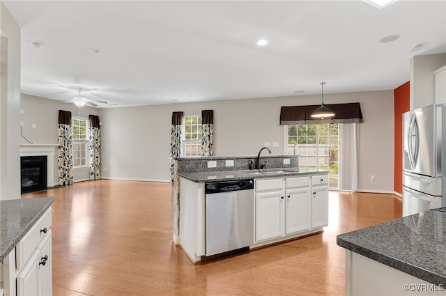 kitchen featuring stainless steel appliances, hanging light fixtures, sink, and white cabinets