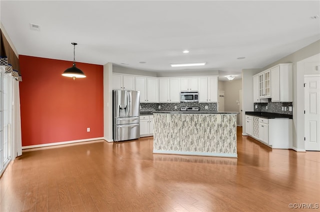 kitchen featuring pendant lighting, hardwood / wood-style floors, white cabinets, and appliances with stainless steel finishes