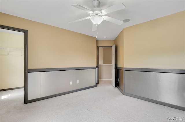 interior space with a spacious closet, light colored carpet, ceiling fan, and a closet