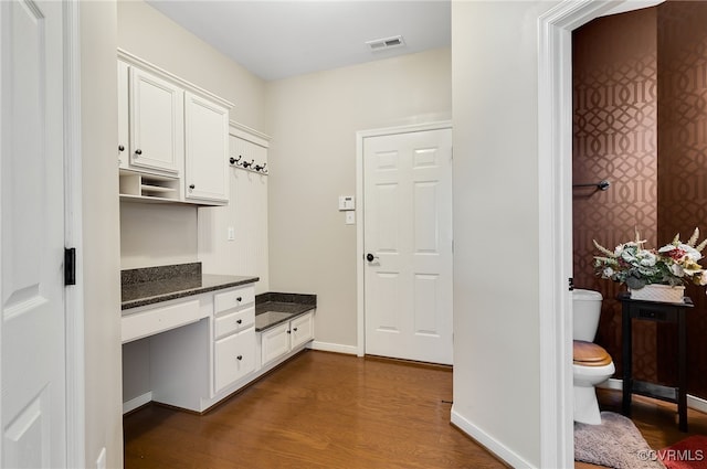 mudroom with dark wood-type flooring and built in desk