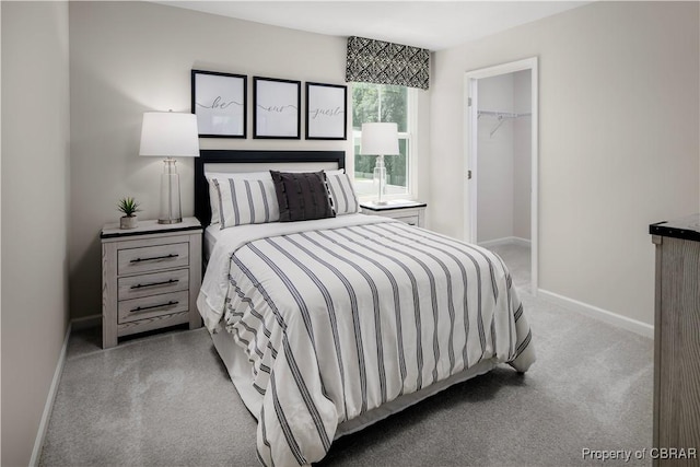 bedroom featuring light colored carpet, a spacious closet, and a closet