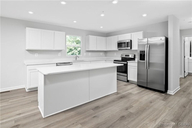 kitchen with white cabinetry, appliances with stainless steel finishes, sink, and a kitchen island